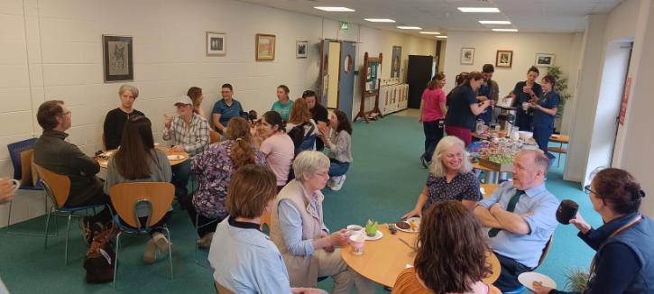 Staff and students at the UCD School of Veterinary Medicine gather for a Pride-themed coffee morning, chatting and enjoying refreshments in a bright communal space decorated with rainbow displays.